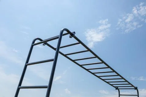 Children play on the monkey bars, reaching for the sky while enjoying a sun.. 库存照片