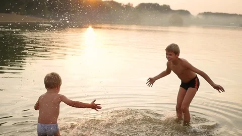 Children play at sea, creating a splash of water. Entertainment and outdoor Vídeo Stock 78879983