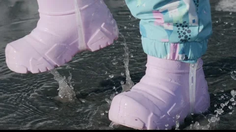 Children play in slow motion while splashing in a puddle during springtime Stock Footage 333646092