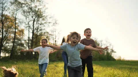 Children play in spring vacation park.Active happy group of kid run with a dog Video stock 195975434