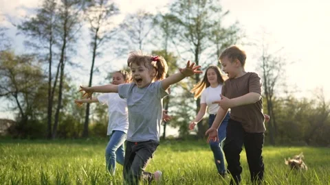 Children play in spring vacation park.Active happy group of kid run with a dog Stock Footage 198556794