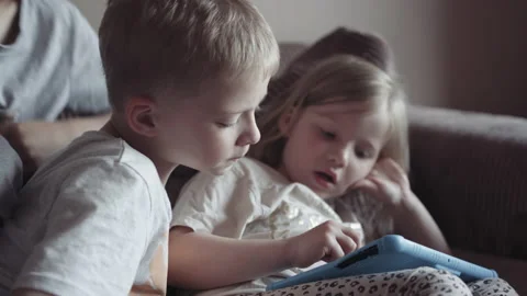 Children play with tablet while sitting on the couch at home. child plays gam Stock Footage 155672790