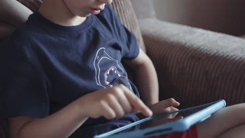 Children play with tablet while sitting on the couch at home. child plays gam Stock Footage 155672810