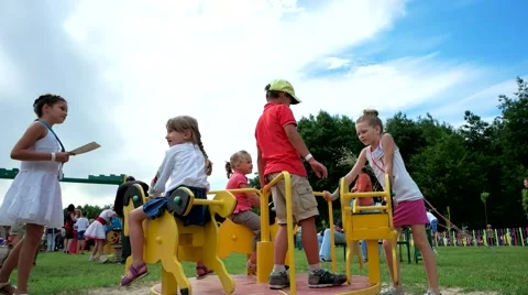 Children in the playground and ride on the carousel steadicam shot Stock Footage