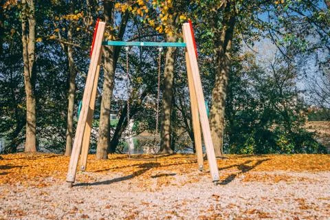 Children playground consisting of swing. Fallen autumn leaves of trees on the Stock Photos