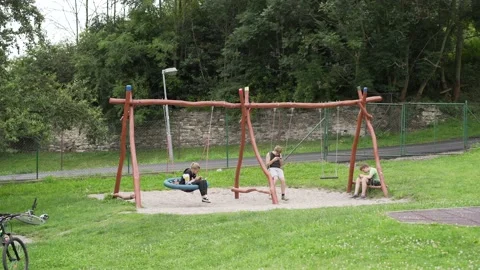 Children on playground sitting on swing and using smartphones Stock Footage 134624853