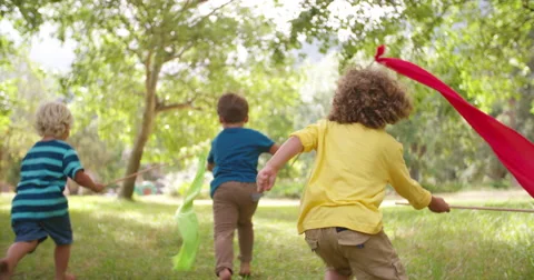 Children playing and running in a park with colorful banners Stock Footage