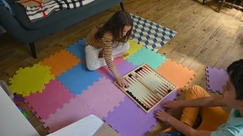 Children playing backgammon on colorful floor mats at home Stock Footage 290052703