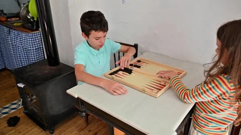 Children playing backgammon at home on a relaxing afternoon Stockbeeldmateriaal 290051476