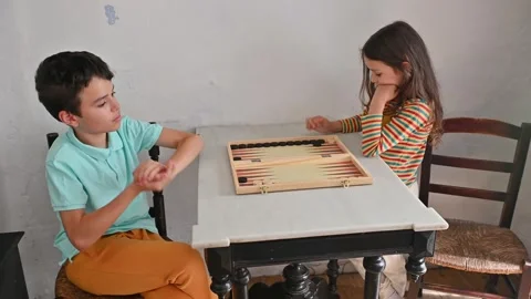 Children playing backgammon at a small table indoors Stock Footage 290049825
