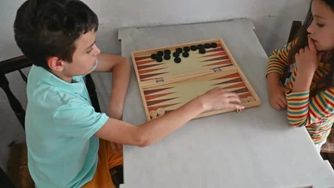 Children playing backgammon at a table for fun and learning Stock Footage 290049096