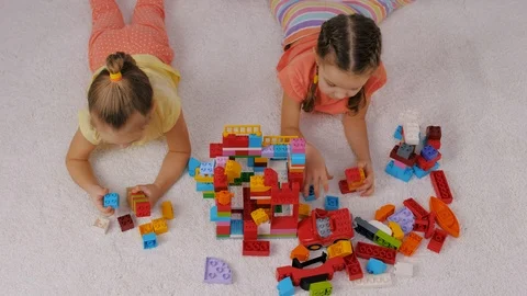 Children playing colorful plastic constructor sitting on carpet in playroom Video stock 124113317