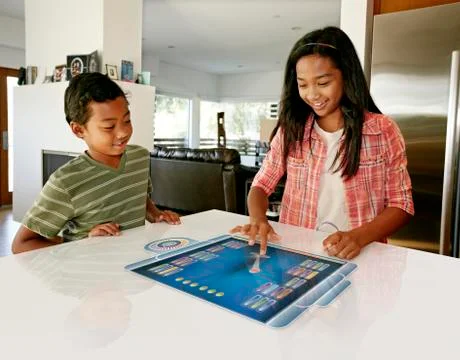 Children playing on computer in table Stock Photos