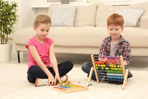 Children playing with different math game kits on floor in living room. Stu.. Stock Photos