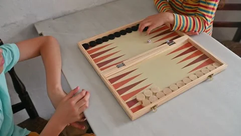 Children playing an engaging game of backgammon at home Stockbeeldmateriaal 290049710