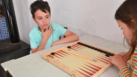 Children playing an engaging game of backgammon at home Stock Footage 290049854
