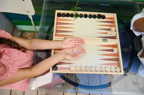 Children playing a game of backgammon together on a glass table Stock Photos