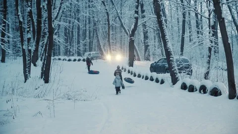 Children playing with inflatable ring in snowy winter forest. Cars parked nearby 스톡 동영상 123298323