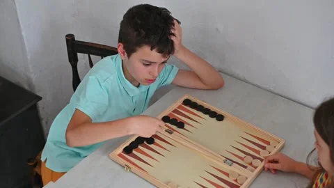 Children playing an intense game of backgammon on a wooden board Stock Footage 290050464