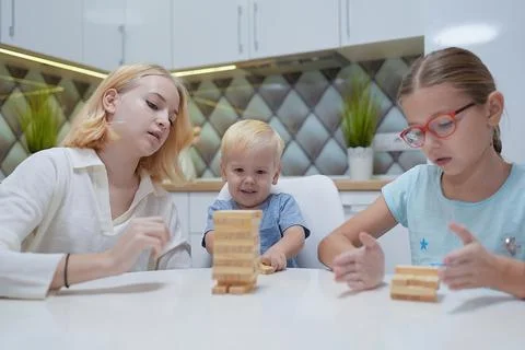 Children playing Jenga tower to remove wooden blocks at home. two girls and b Stock Photos