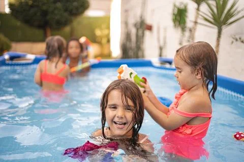 Children playing joyfully in a backyard pool on a sunny day Stock Photos
