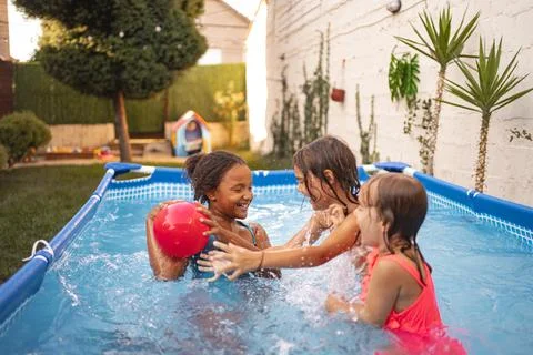 Children playing joyfully in backyard pool on a sunny afternoon Stock Photos