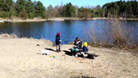 Children playing by the lake while building sandcastles and enjoying a sunny Stock Footage 306438679