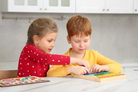 Children playing with math game kit at white marble table in kitchen. Learn.. Stock Photos