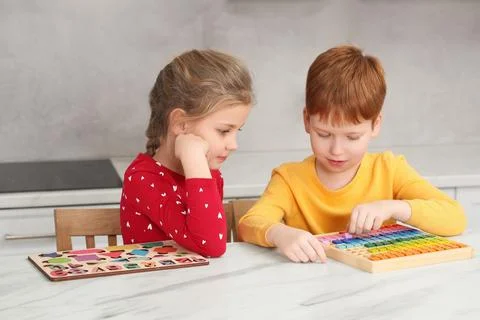 Children playing with math game kit at white marble table in kitchen. Learn.. Stock Photos