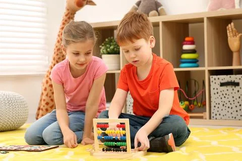 Children playing with math game kit on floor in room. Learning mathematics .. Stock Photos