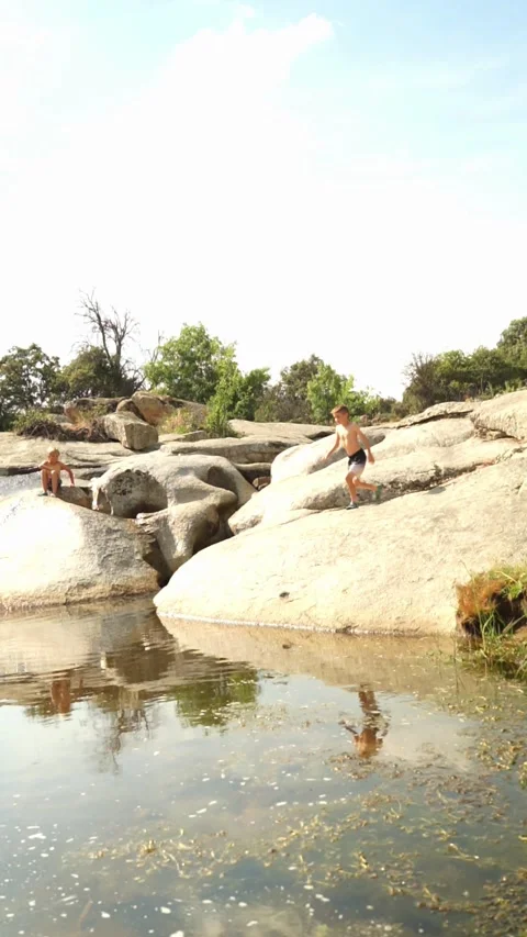 Children playing in the river in summer. Boy jumping into a natural pool Stock Footage 277454002