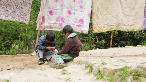Children playing with rocks and clothes hanging for dry on a sunny day Stock Footage 77449637