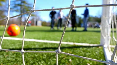 Children playing soccer game, camera behind the goal net Stock Footage