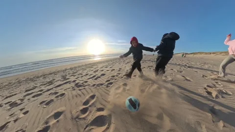 Children playing soccer on a sandy beach at sunset Stock Footage 330518516