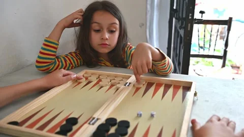 Children playing strategic game of backgammon indoors on a sunny day Stock Footage 290050978
