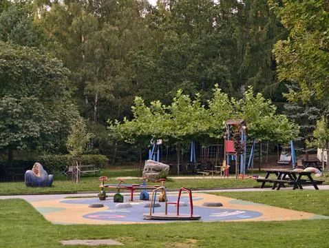 Children playing under green trees, serene park environment with colorful Stock Photos