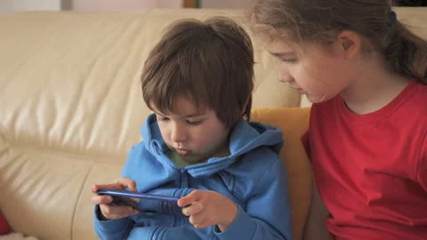 Children Playing Video Games In Mobile Phone at Home Sitting on Couch. Mobi.. 库存影片 335592389