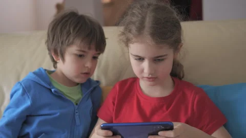 Children Playing Video Games In Mobile Phone at Home Sitting on Couch. Mobi.. 库存影片 335599249