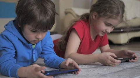 Children Playing Video Games In Mobile Phone at Home Lying on Floor. Mobile.. Video stock 335634237