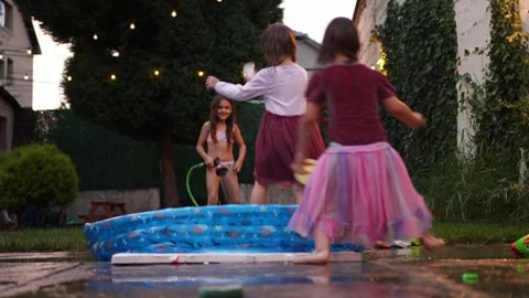 Children playing with water in backyard inflatable pool Stock Footage 316482870