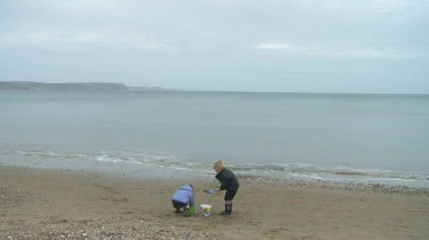 Children Playing on Weymouth Beach on Overcast Day Stock Footage