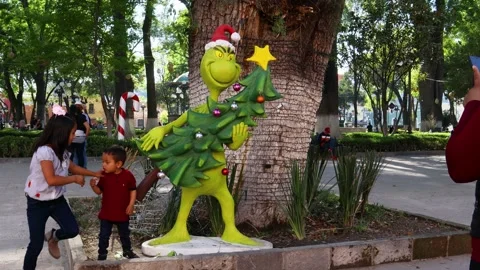 Children posing with a figure of the Grinch while their mother takes photos Stock Footage 171691538