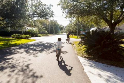 Children, a pre teenager and her brother cycling on a suburban road Stock Photos