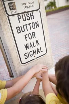 Children pressing a button at traffic lights on pedestrian crossing and havin Stock Photos