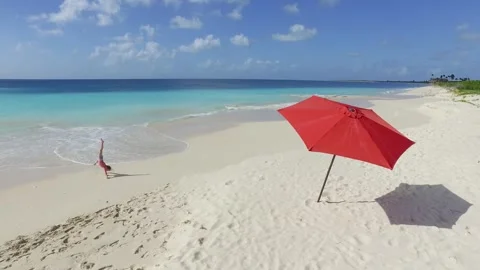 Children on a pristine beach with a red umbrella. Stock Footage 301466924