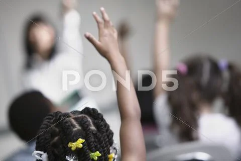 Children raising hands in classroom Stock Photos