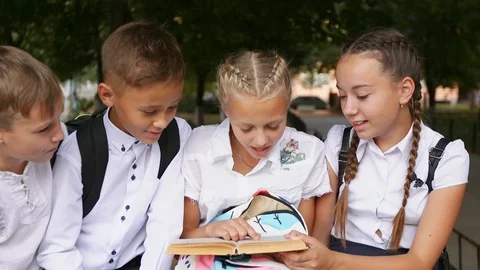 Children read a textbook in the schoolyard Stock Footage 94331358