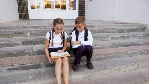 Children read a textbook in the schoolyard 库存影片 94331422