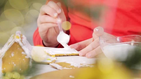 Children in red sweaters decorate baked sweet gingerbread house. Decorated Stock Footage 258181253