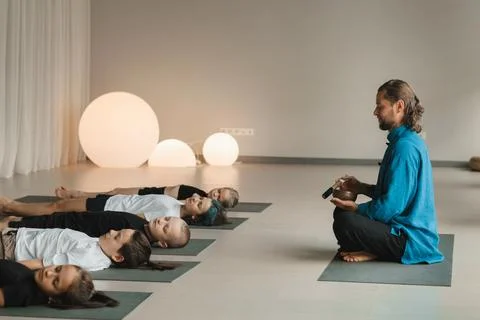 Children relax lying down to the sounds of a Tibetan bowl in the fitness room Fotos de archivo